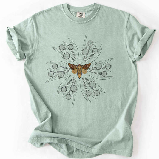 Bay endangered moth t-shirt on Comfort Colors tee, featuring a realistic Rattlesnake Master Borer Moth (Papaipema eryngii) at the center of a mandala style burst of hand drawn thistle flowers. Nature lover and moth enthusiast gift shirt for entomology and botanical illustration fans.