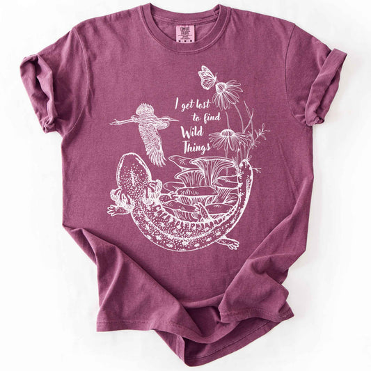 Berry "I Get Lost to Find Wild Things" t-shirt on Comfort Colors tee, featuring a curled mudpuppy salamander, heron, mushrooms, monarch and coneflowers line art style. Nature lover and hiking gift shirt for salamander and wildlife enthusiasts.