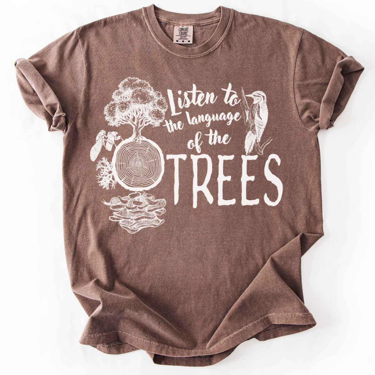 Espresso "Listen to the Language of the Trees" t-shirt on Comfort Colors tee, featuring a tree, tree rings, woodpecker, cicada, and mushrooms in white. Nature lover and forest ecology gift shirt for tree huggers and outdoor enthusiasts.
