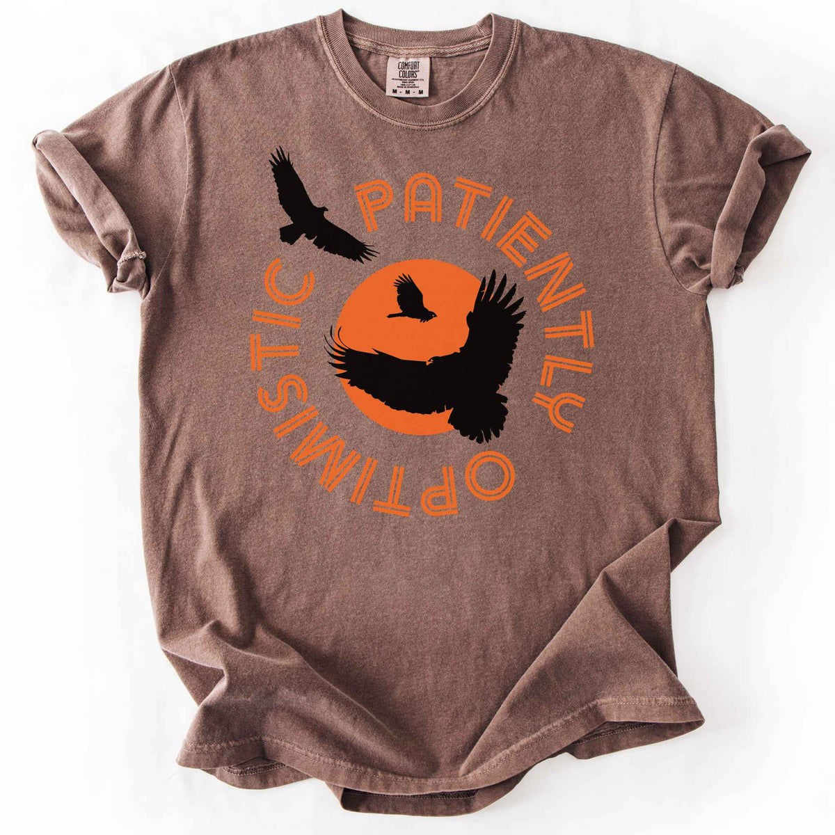 Espresso "Patiently optimistic turkey vulture" t-shirt on comfort colors tee. Silhouette turkey vulture graphics against an orange sun surrounded by curved text. Bird lover and wildlife enthusiast gift.