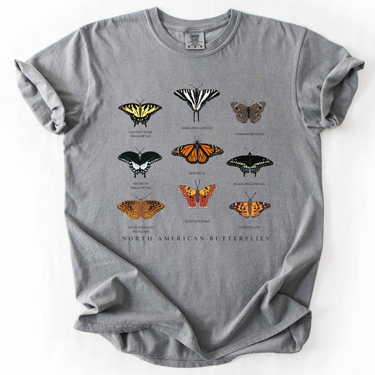 Grey "North American Butterflies" comfort colors t-shirt. Nine illustrated and titled species including the Eastern Tiger Swallowtail, Zebra Swallowtail, Common Buckeye, Monarch, Black Swallowtail, Spicebush Swallowtail, Painted Lady, Great Spangled Fritillary, and Question Mark butterflies. Butterfly lover gift and wildlife gardening enthusiast apparel.