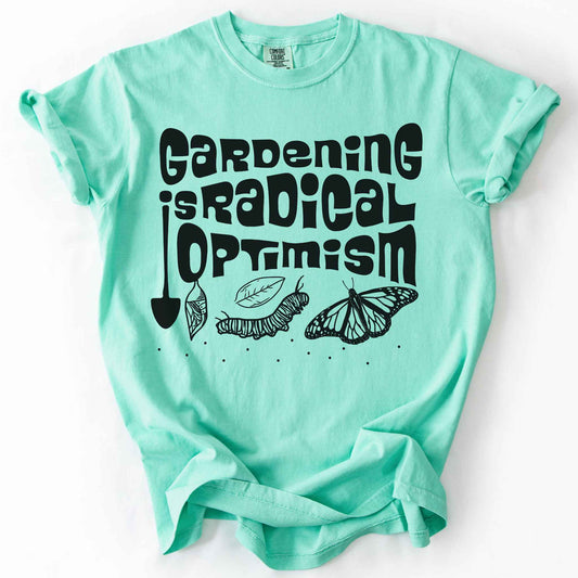 Island reef "Gardening Is Radical Optimism" t-shirt on Comfort Colors tee, featuring a butterfly life cycle illustration with a garden shovel and retro lettering. Gardener and native plant gift shirt for pollinator and butterfly conservation fans.