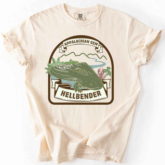 Ivory "Appalachian Gem, Hellbender" t-shirt on Comfort Colors tee, featuring a vintage style badge with a hellbender salamander over a mountain river scene and banner lettering. Amphibian and herpetology lover gift shirt for salamander and Appalachian wildlife enthusiasts.