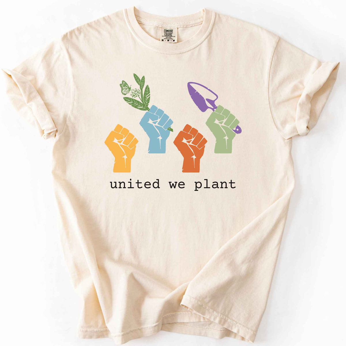 Ivory "United We Plant" t-shirt on Comfort Colors tee, featuring four colorful raised fists, one holding a plant sprig and another a garden trowel, above bold black text. Gardener and native plant gift shirt for community garden and conservation enthusiasts.