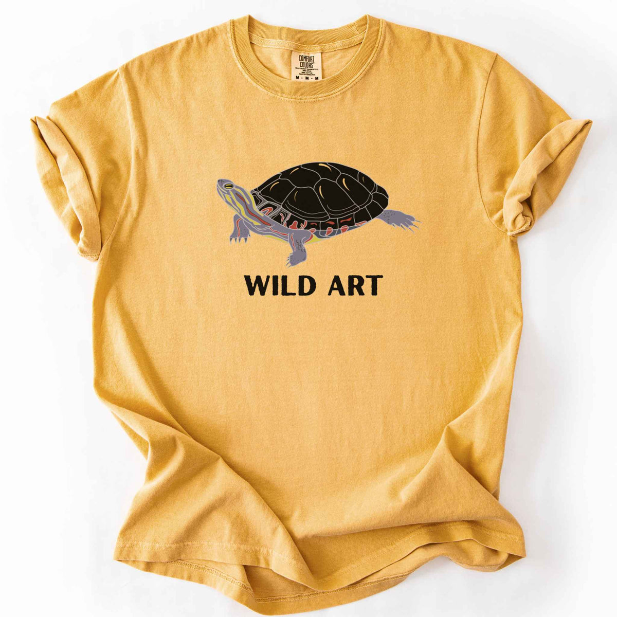 Mustard "Wild Art" t-shirt on Comfort Colors tee, featuring a bold graphic of a painted turtle with bold black text below. Reptile lover and turtle enthusiast gift shirt for wildlife and nature fans.