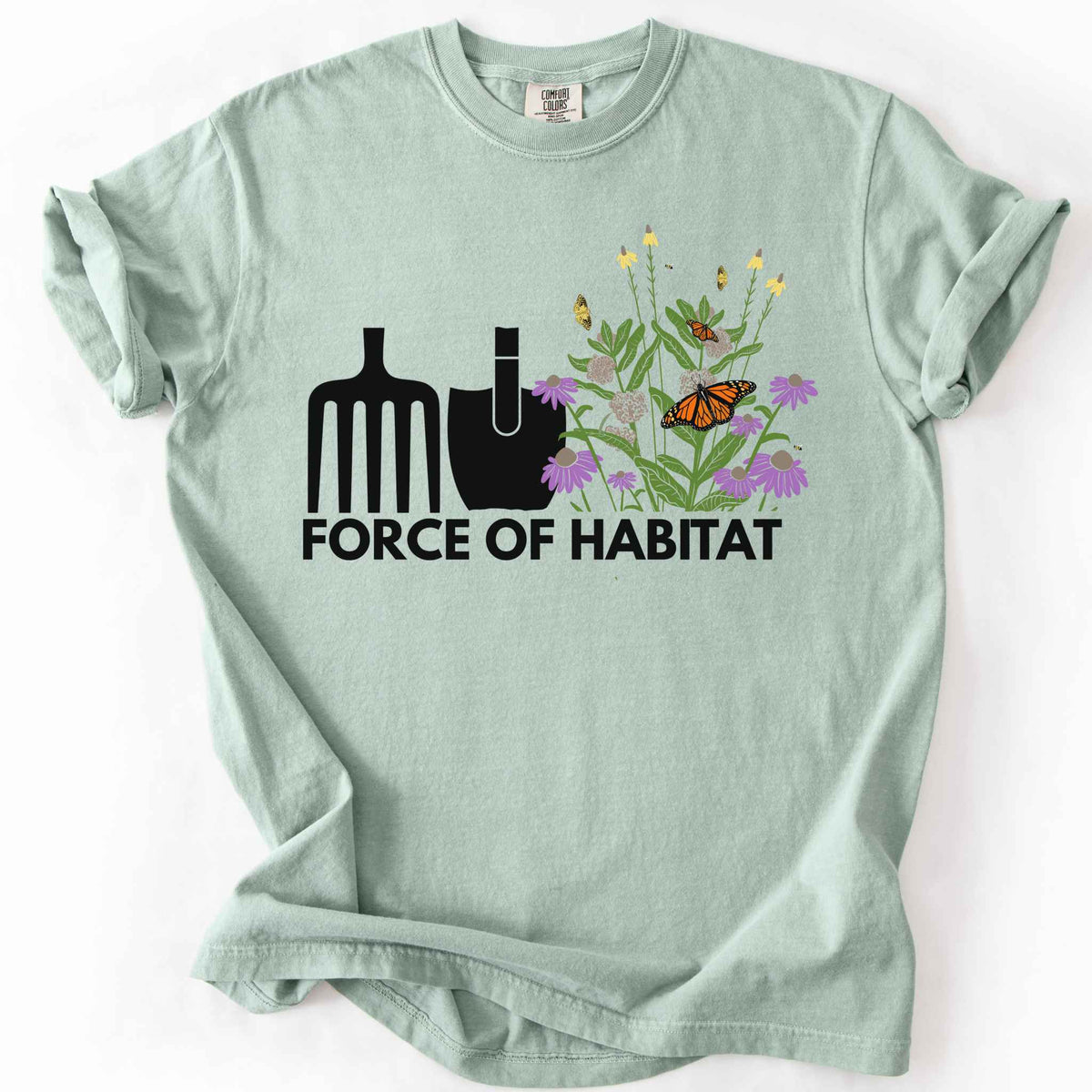 Bay "Force of Habitat" t-shirt on Comfort Colors tee, featuring simple garden tool graphics beside a coneflower and milkweed patch with monarch and fritillary butterflies. Gardener and native plant gift shirt for pollinator conservation fans.