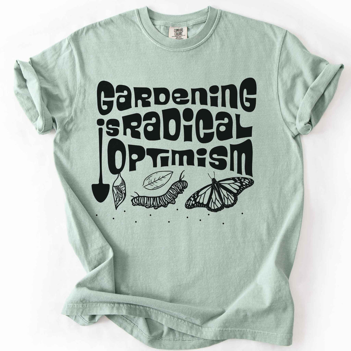 Bay "Gardening Is Radical Optimism" t-shirt on Comfort Colors tee, featuring a butterfly life cycle illustration with a garden shovel and retro lettering. Gardener and native plant gift shirt for pollinator and butterfly conservation fans.