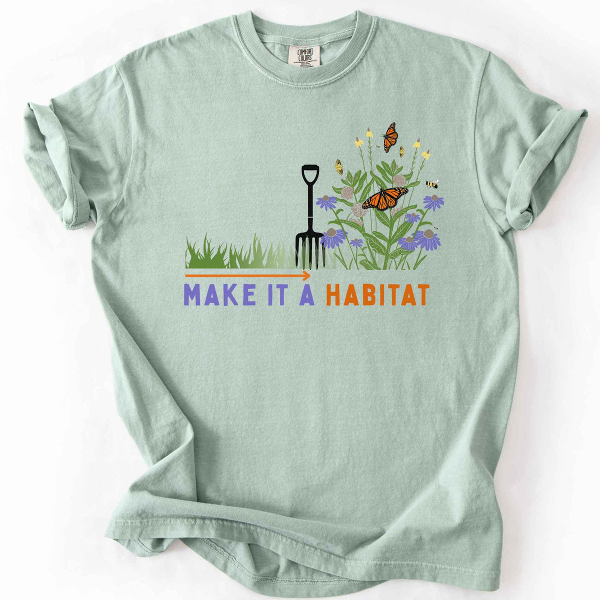 Bay "Make It a Habitat" t-shirt on Comfort Colors tee, featuring a garden fork beside coneflowers and milkweed with monarch butterflies and bees, transforming grass into wildflowers. Gardener and native plant gift shirt for pollinator conservation fans.