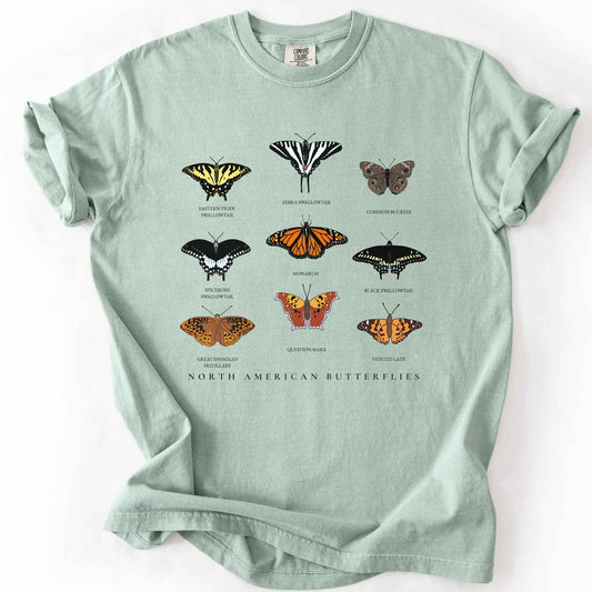 Bay "North American Butterflies" comfort colors t-shirt. Nine illustrated and titled species including the Eastern Tiger Swallowtail, Zebra Swallowtail, Common Buckeye, Monarch, Black Swallowtail, Spicebush Swallowtail, Painted Lady, Great Spangled Fritillary, and Question Mark butterflies. Butterfly lover gift and wildlife gardening enthusiast apparel. 