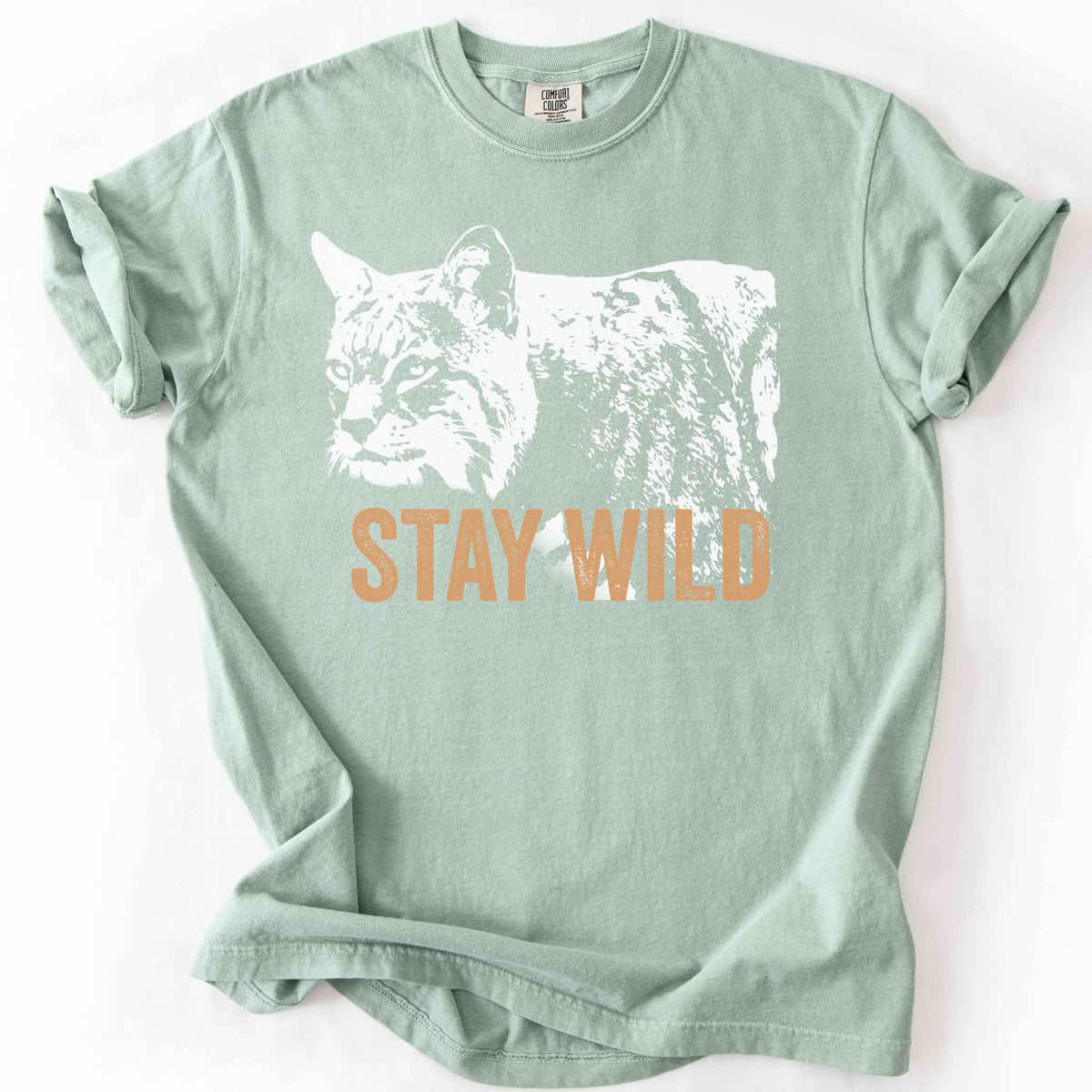 Bay "Stay Wild" t-shirt on Comfort Colors tee, featuring a bold white bobcat graphic with orange lettering — wildlife lover and nature enthusiast gift shirt for outdoorsy, animal-inspired style.