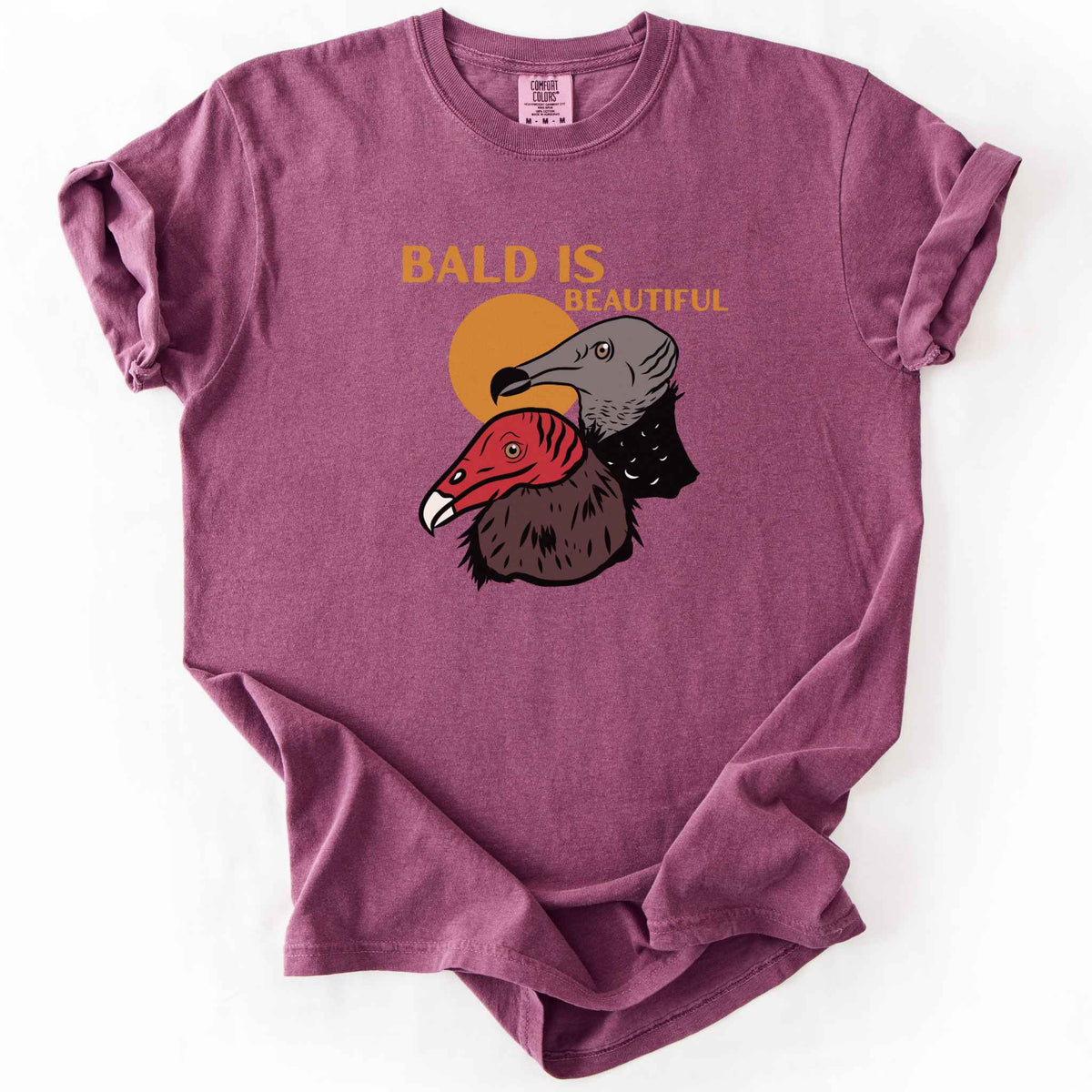 Berry "Bald Is Beautiful" t-shirt on Comfort Colors tee, featuring illustrated turkey vulture and black vulture heads with orange retro sun and orange lettering. Funny birdwatcher gift shirt for vulture and scavenger lovers.