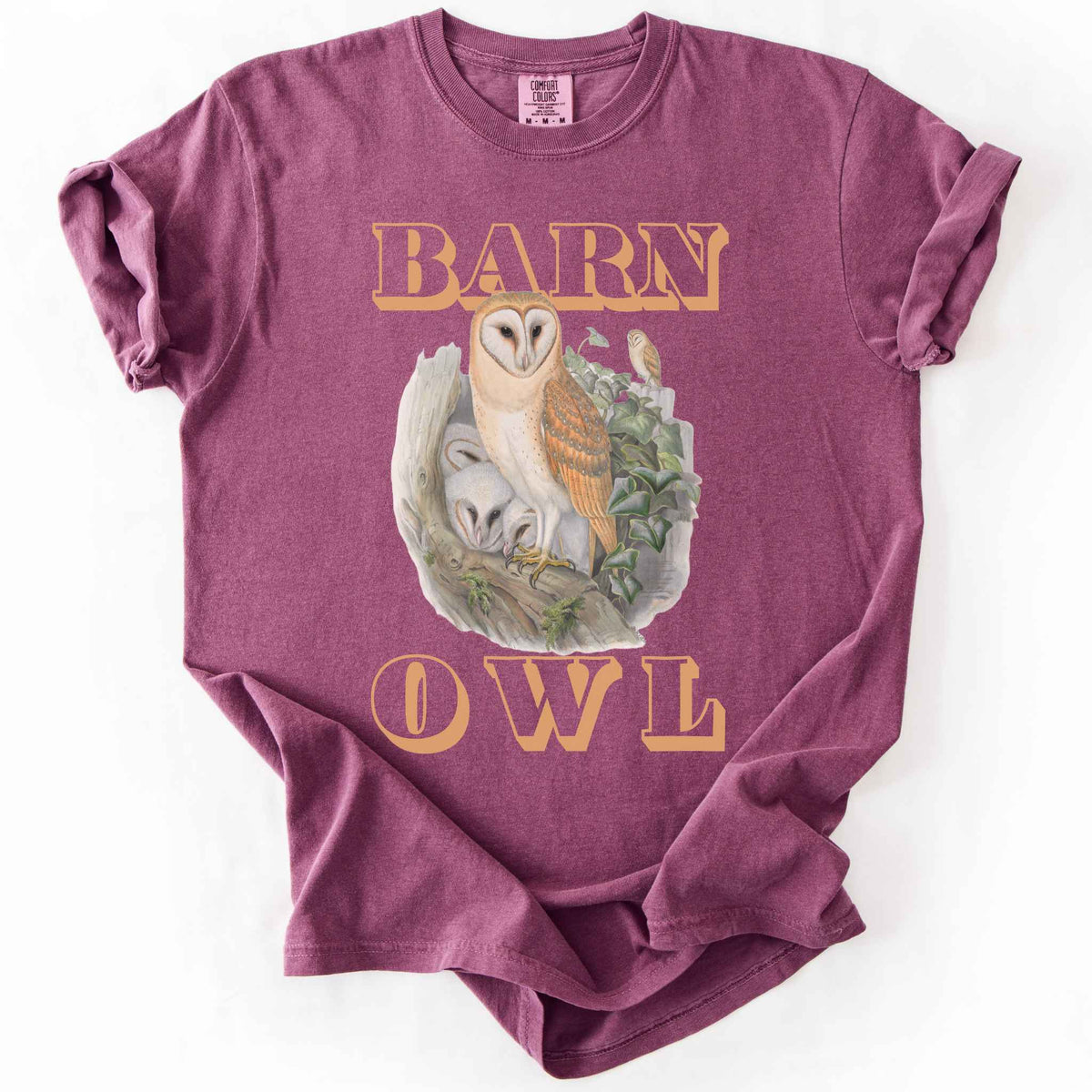 Berry "Barn Owl" t-shirt on Comfort Colors tee, featuring a detailed graphic of a barn owl with owlets nestled in a tree hollow with ivy, in tan bold lettering. Birdwatcher and owl lover gift shirt for wildlife and nature enthusiasts.
