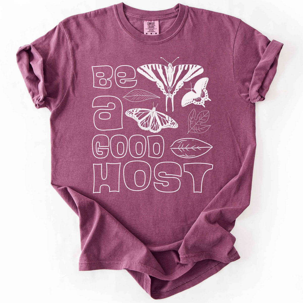 Berry "Be a good host" t-shirt on Comfort colors with illustrations of zebra swallowtail and host plant paw paw leaf, spicebush swallowtail and one of its host plants sassafras leaf, and monarch and host plant milkweed leaf. Gift for wildlife gardeners and native plant enthusiasts.