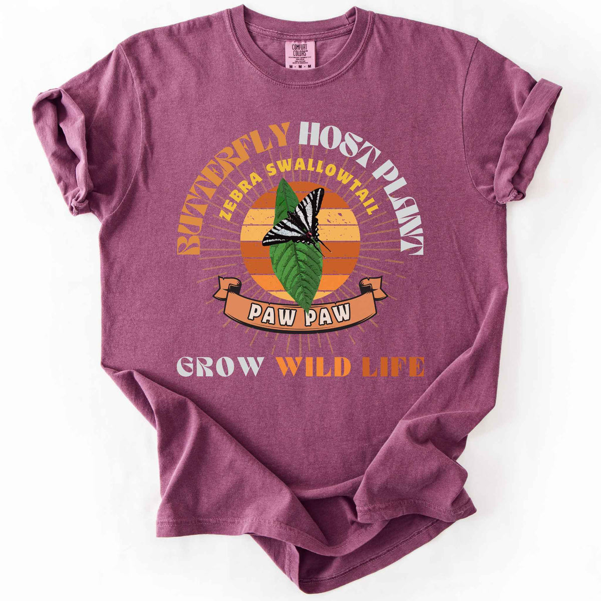 Berry "Butterfly Host Plant, Zebra Swallowtail, Paw Paw, Grow Wild Life" t-shirt on Comfort Colors tee, featuring a zebra swallowtail on a pawpaw leaf against a retro sunburst design with a ribbon banner. Butterfly gardener and native plant gift shirt for pollinator and conservation enthusiasts.