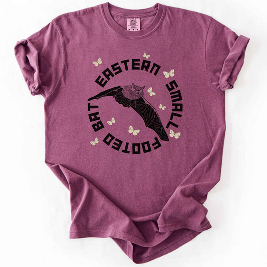 Berry "Eastern Small Footed Bat" t-shirt on Comfort Colors tee, featuring a black illustration of a flying bat surrounded by pale moths in a circular badge design. Bat lover and wildlife gift shirt for nocturnal animal and nature enthusiasts.
