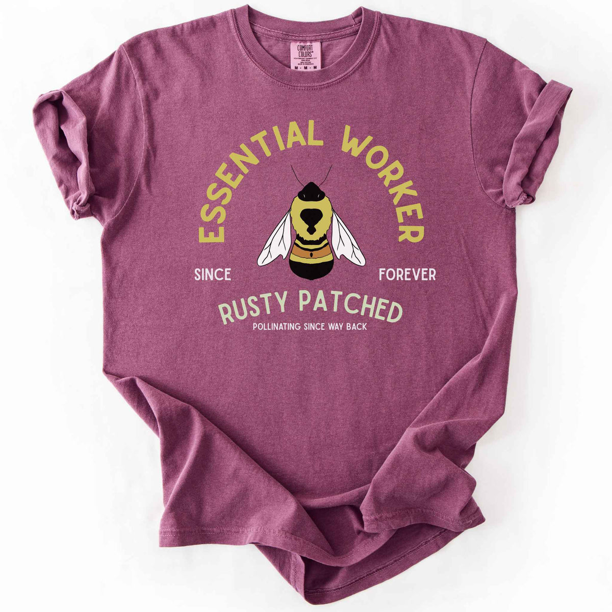 Berry "Essential Worker, Rusty Patched, Pollinating Since Way Back" t-shirt on Comfort Colors tee, featuring an illustrated bumblebee in a circular design. Funny bee lover gift shirt for pollinator and rusty patched bumblebee conservation fans.