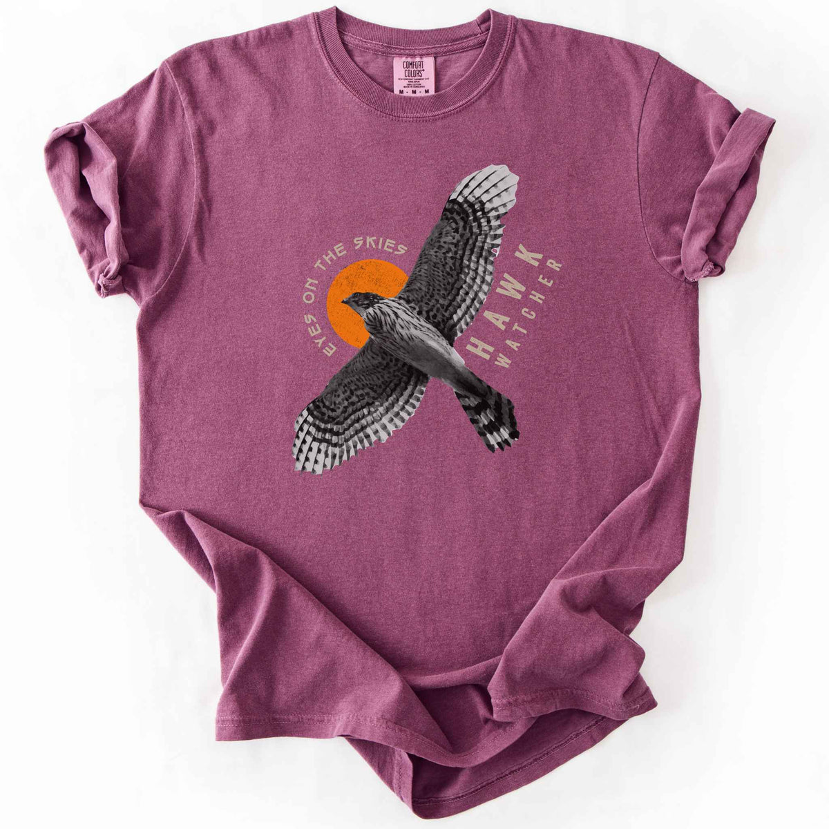 Berry "Hawk Watcher, Eyes on the Skies" t-shirt on Comfort Colors tee, featuring a flying hawk graphic with spread wings against an orange sun design- birdwatching and raptor lover gift shirt for bird enthusiasts.