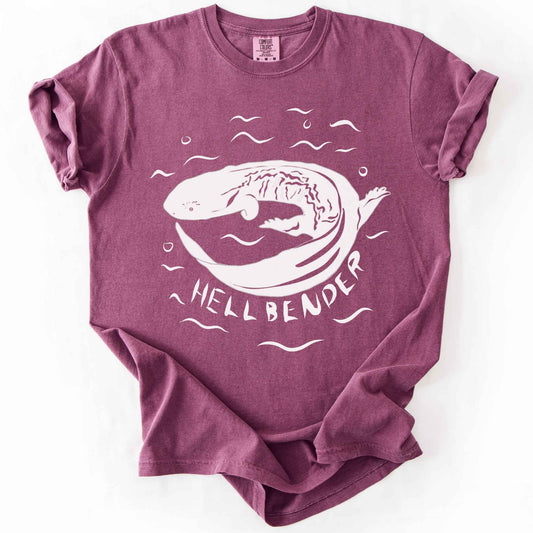 Berry "Hellbender" t-shirt on Comfort Colors tee, featuring a bold graphic of a curled hellbender salamander surrounded by stylized water splashes and bubbles. Amphibian and herpetology lover gift shirt for salamander and wildlife enthusiasts.