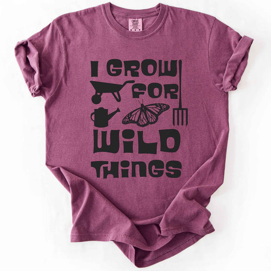 Berry "I Grow for Wild Things" t-shirt on Comfort Colors tee, featuring a monarch butterfly with garden tool icons and bold black lettering text. Gardener and native plant gift shirt for pollinator conservation fans.
