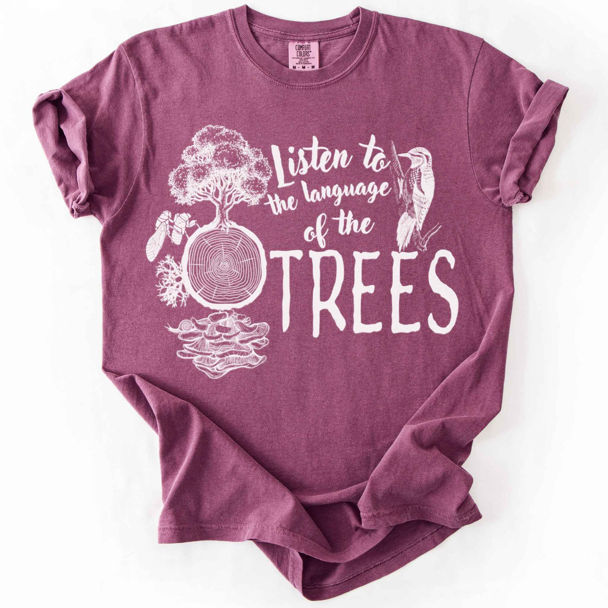 Berry "Listen to the Language of the Trees" t-shirt on Comfort Colors tee, featuring a tree, tree rings, woodpecker, cicada, and mushrooms in white. Nature lover and forest ecology gift shirt for tree huggers and outdoor enthusiasts.