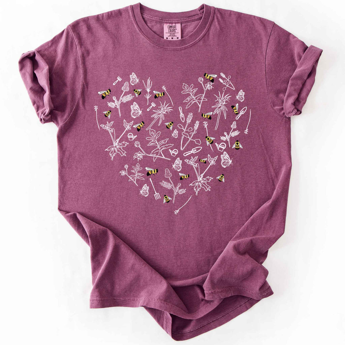 Berry "Rusty Patch Bumblebee" t-shirt on Comfort Colors tee, featuring a heart shaped arrangement of hand-drawn white wildflowers, garden tools, butterflies, and colorful bees. Gardener and pollinator lover gift shirt for bee conservation and nature enthusiasts.