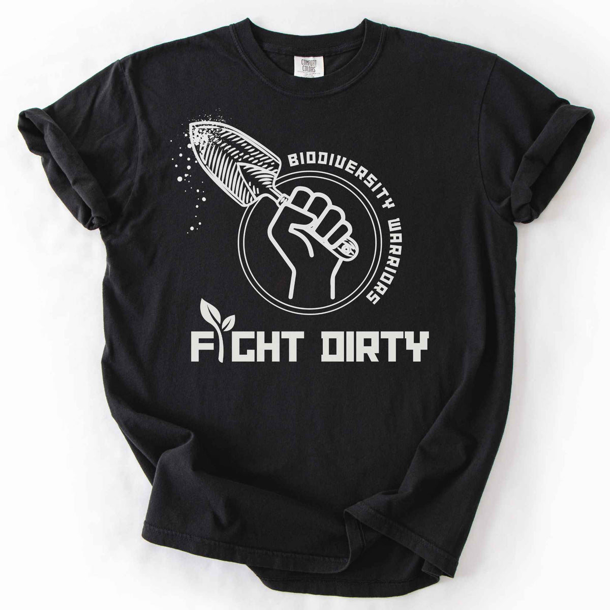 Black "Biodiversity Warriors, Fight Dirty" t-shirt on Comfort Colors tee, featuring a raised fist gripping a garden trowel in a circular badge design. Gardener and conservation lover gift shirt for native plant and biodiversity enthusiasts.