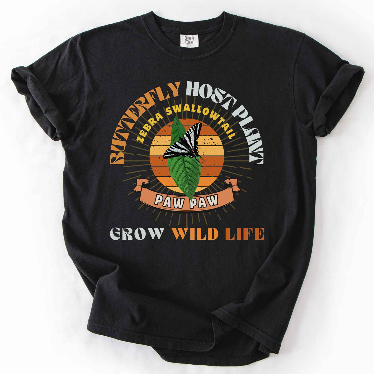 Black "Butterfly Host Plant, Zebra Swallowtail, Paw Paw, Grow Wild Life" t-shirt on Comfort Colors tee, featuring a zebra swallowtail on a pawpaw leaf against a retro sunburst design with a ribbon banner. Butterfly gardener and native plant gift shirt for pollinator and conservation enthusiasts.