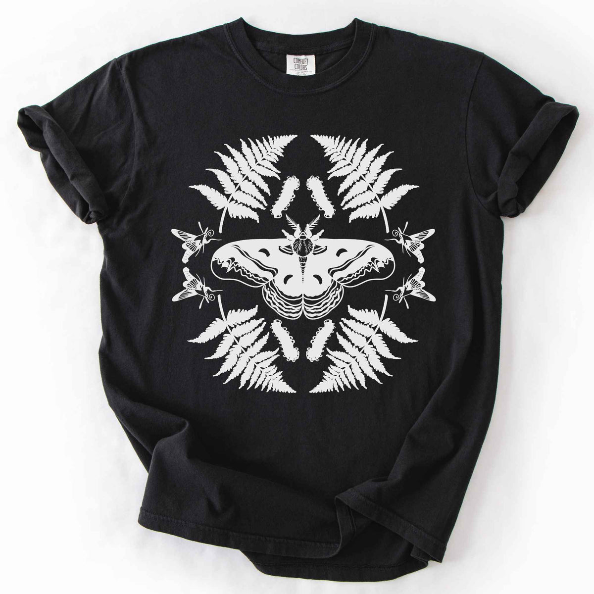 Black "Cecropia moth" t-shirt on Comfort Colors tee, featuring a bold black symmetrical design of a moth surrounded by ferns and hummingbird moths in a mirrored botanical pattern. Nature lover and moth enthusiast gift shirt for entomology and cottagecore fans.