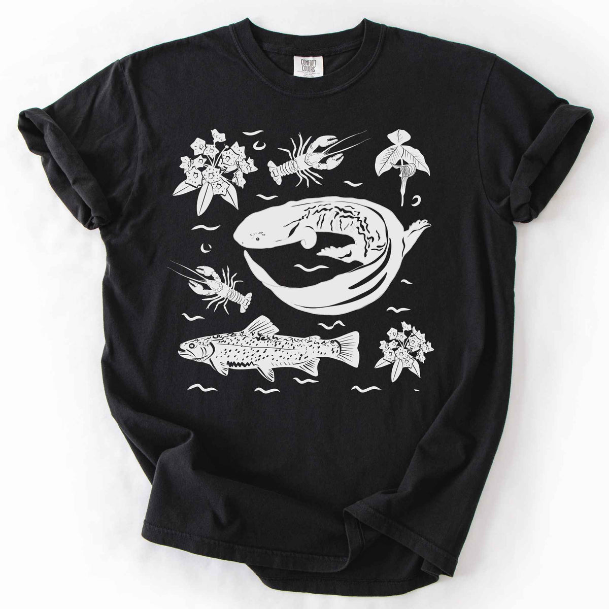 Black "Hellbender Ecology" t-shirt on Comfort Colors tee, featuring a curled hellbender salamander surrounded by hand-drawn crayfish, trout, and mountain laurel. Amphibian and river ecosystem gift shirt for herpetology and fly fishing enthusiasts.