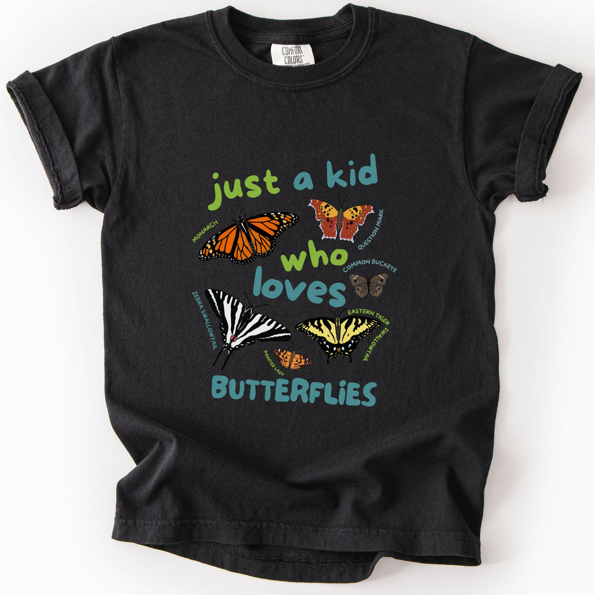 Black "Just a Kid Who Loves Butterflies" youth t-shirt on Comfort Colors tee, featuring six labeled butterfly species including Monarch, Zebra Swallowtail, and Painted Lady with playful green and teal lettering. Kids butterfly lover gift shirt for young nature explorers and budding entomologists.