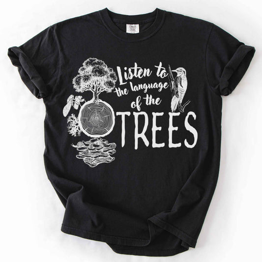 Black "Listen to the Language of the Trees" t-shirt on Comfort Colors tee, featuring a tree, tree rings, woodpecker, cicada, and mushrooms in white. Nature lover and forest ecology gift shirt for tree huggers and outdoor enthusiasts.