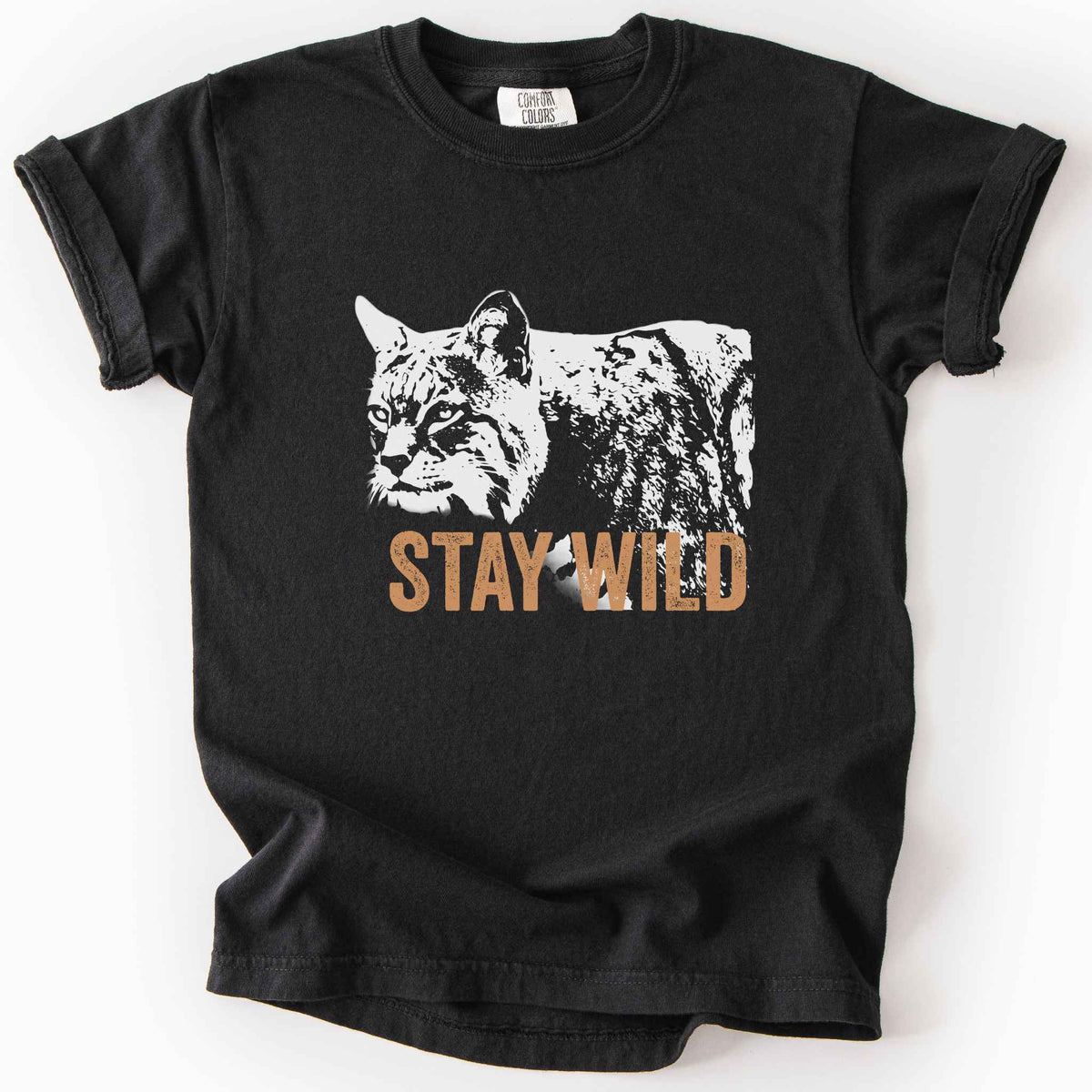 Black "Stay Wild" kids t-shirt on Comfort Colors tee, featuring a bold white bobcat graphic with orange lettering — wildlife lover and nature enthusiast gift shirt for outdoorsy, animal-inspired style.