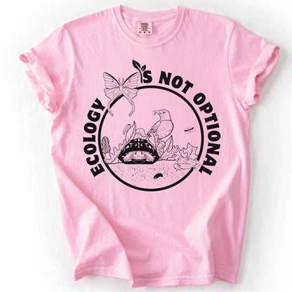 Blossom "Ecology Is Not Optional" t-shirt on Comfort Colors tee, featuring a black circle badge with a box turtle, bird, luna moth, frog, and mushrooms in an ecosystem scene. Nature lover and biology gift shirt for ecologists and conservation enthusiasts.