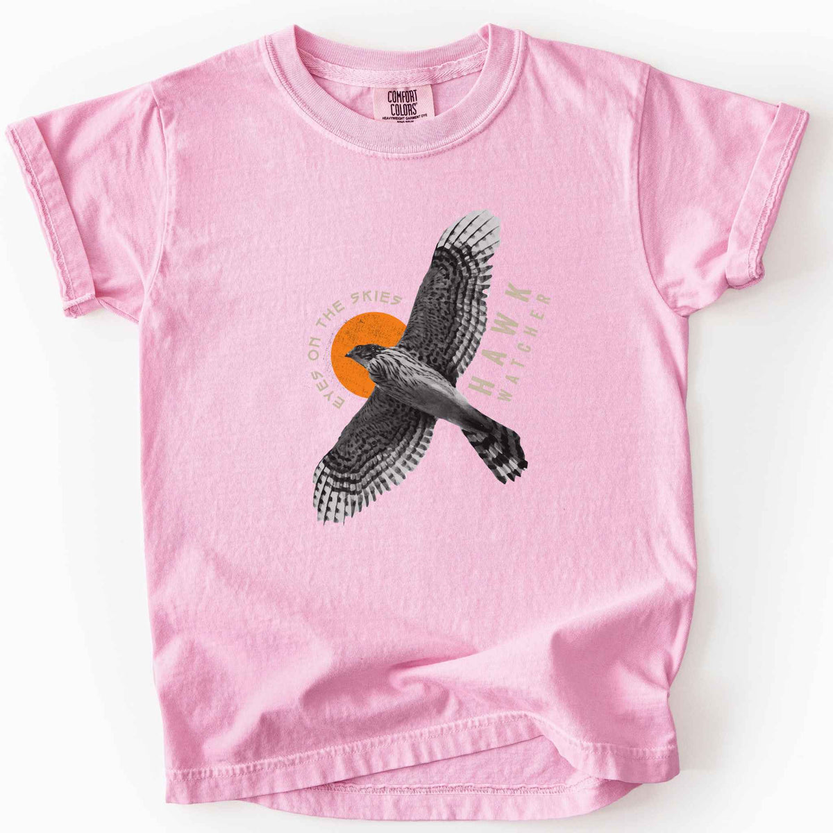 Blossom "Hawk Watcher, Eyes on the Skies" t-shirt on Comfort Colors tee, featuring a flying hawk graphic with spread wings against an orange sun design- birdwatching and raptor lover gift shirt for bird enthusiasts.
