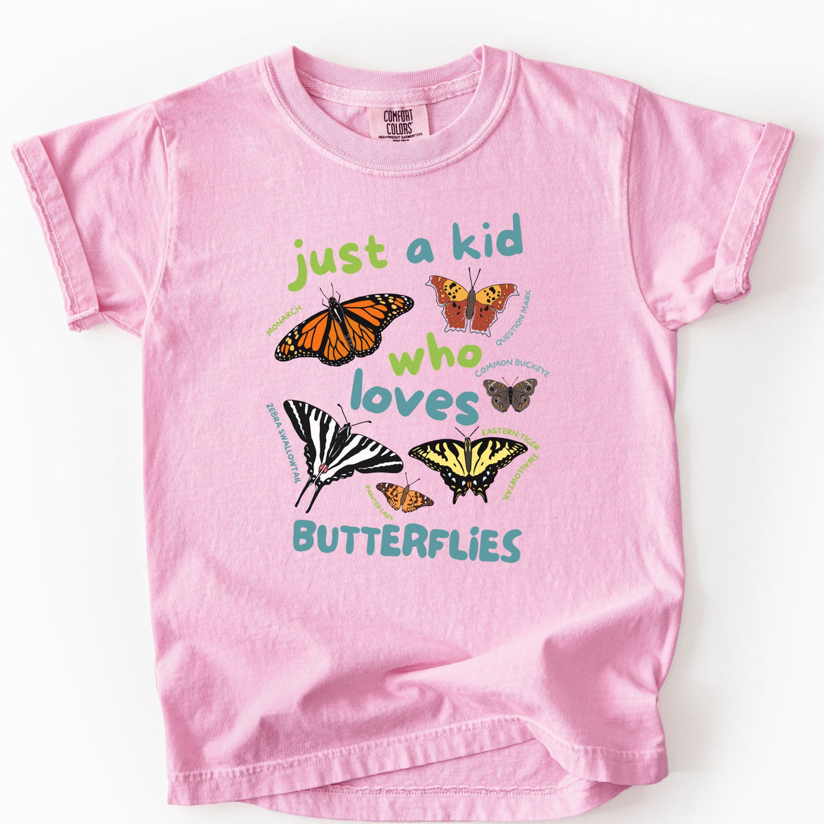 Blossom "Just a Kid Who Loves Butterflies" youth t-shirt on Comfort Colors tee, featuring six labeled butterfly species including Monarch, Zebra Swallowtail, and Painted Lady with playful green and teal lettering. Kids butterfly lover gift shirt for young nature explorers and budding entomologists.
