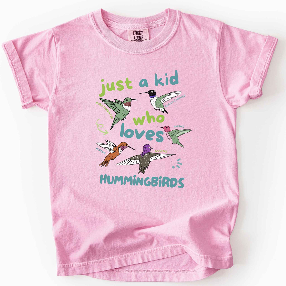 Blossom "Just a Kid Who Loves Hummingbirds" youth t-shirt on Comfort Colors tee, featuring five labeled hummingbird species including Ruby Throated, Anna's, and Costa's with playful green and blue lettering. Kids birdwatcher gift shirt for young nature lovers and budding wildlife enthusiasts.