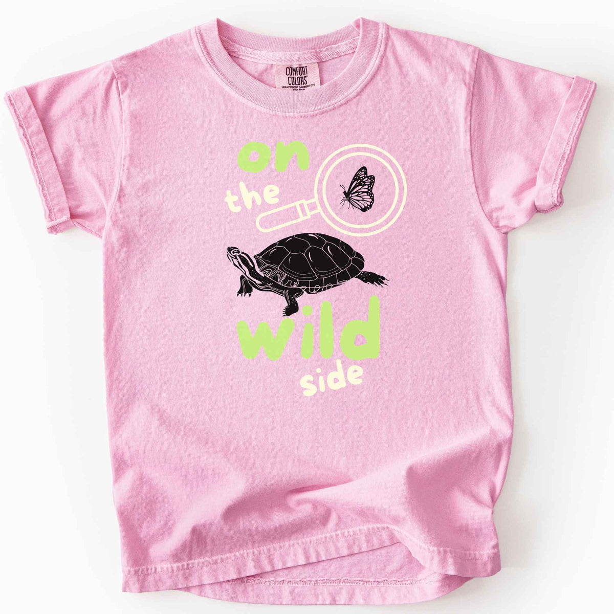 Blossom "On the wild side" kids t-shirt on Comfort Colors tee featuring a butterfly in a magnifying glass and painted turtle graphic with bold and playful text. Nature lover kids shirt for wildlife and exploration enthusiasts. 