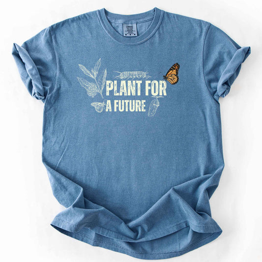 Blue Jean "Plant for a Future" t-shirt on Comfort Colors tee, featuring the Monarch butterfly life cycle from caterpillar to chrysalis alongside milkweed graphic in cream tones. Butterfly gardener and native plant gift shirt for Monarch conservation fans.