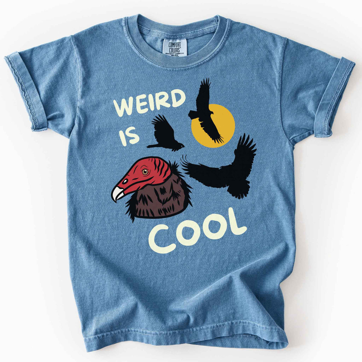 Blue Jean "Weird is cool" kids t-shirt on comfort colors tee featuring turkey vulture silhouettes and a hand-drawn profile graphic with bold white playful text. Gift for little beginning birders and wildlife enthusiasts. 