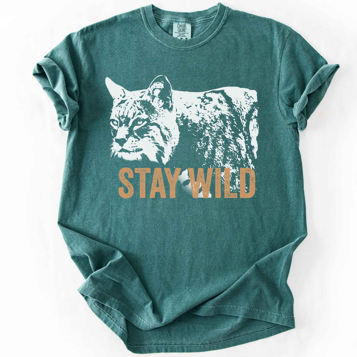 Blue Spruce "Stay Wild" t-shirt on Comfort Colors tee, featuring a bold white bobcat graphic with orange lettering — wildlife lover and nature enthusiast gift shirt for outdoorsy, animal-inspired style. 