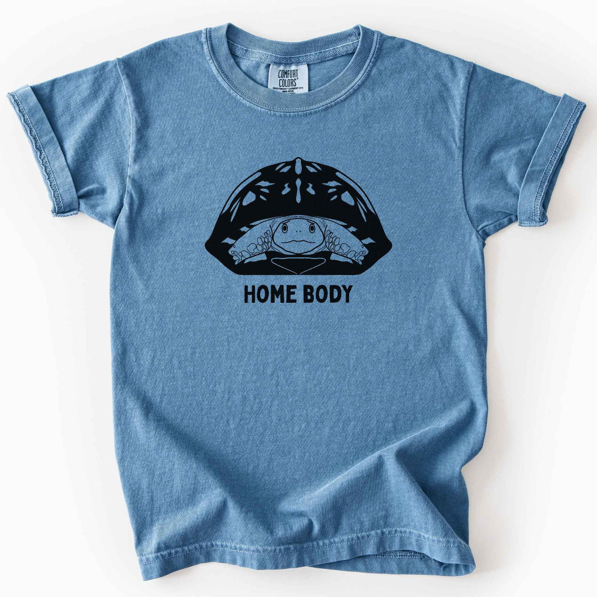 Blue jean "Home Body" kids t-shirt on Comfort Colors tee, featuring a bold black graphic of a turtle peeking out from its shell above simple lettering. Funny turtle lover gift shirt for introverts and reptile enthusiasts.