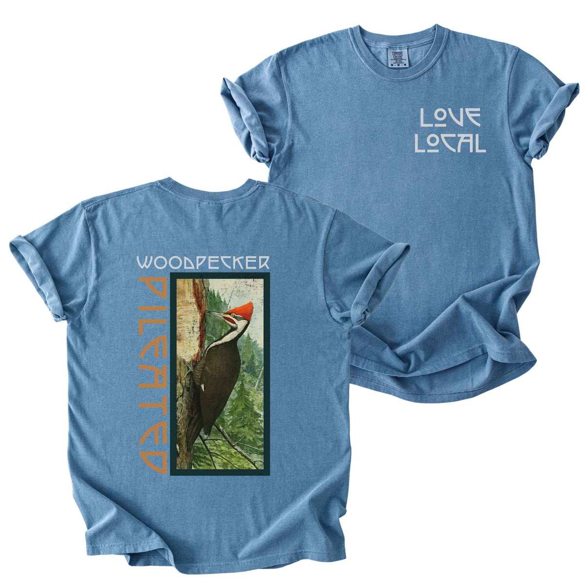 Blue jean "Pileated Woodpecker, Love Local" t-shirt on Comfort Colors tee, featuring a small front chest logo and a full vintage style back print of a woodpecker on a tree in a forest setting. Birdwatcher gift shirt for wildlife and nature enthusiasts.