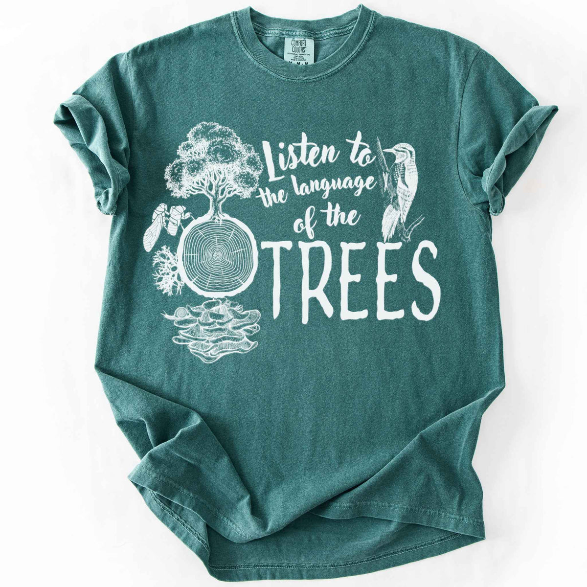 Blue spruce "Listen to the Language of the Trees" t-shirt on Comfort Colors tee, featuring a tree, tree rings, woodpecker, cicada, and mushrooms in white. Nature lover and forest ecology gift shirt for tree huggers and outdoor enthusiasts.