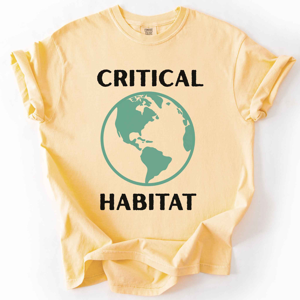 Butter "Critical Habitat" t-shirt on Comfort Colors tee, featuring a bold green globe graphic with black lettering. Conservation and environmentalist gift shirt for earth science and wildlife protection advocates.