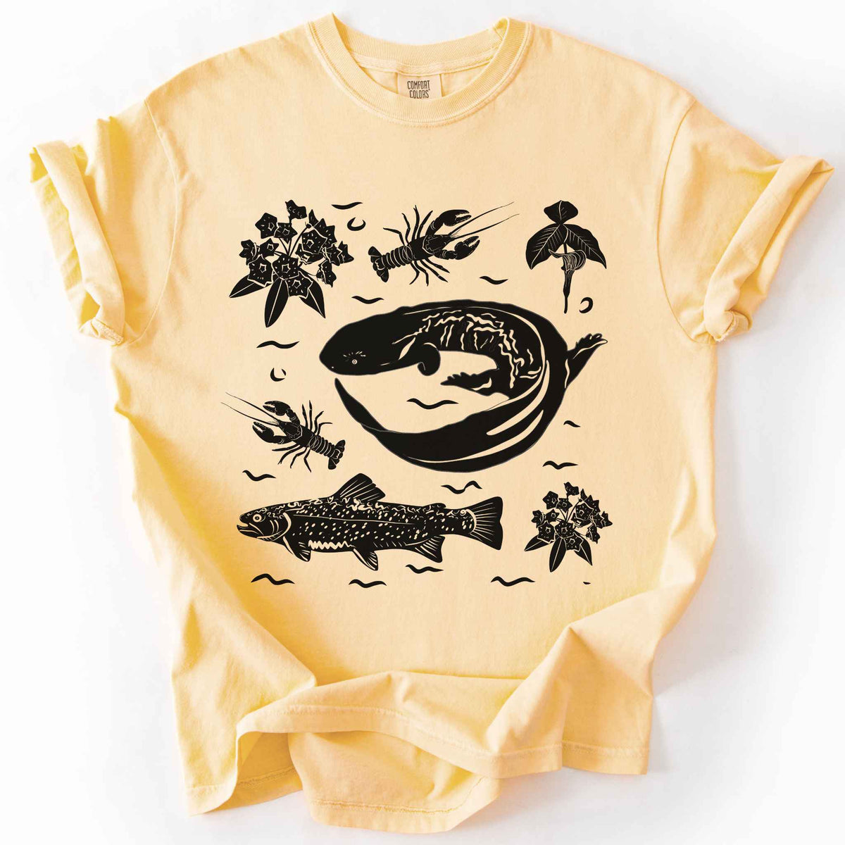 Butter "Hellbender Ecology" t-shirt on Comfort Colors tee, featuring a curled hellbender salamander surrounded by hand-drawn crayfish, trout, and mountain laurel. Amphibian and river ecosystem gift shirt for herpetology and fly fishing enthusiasts.