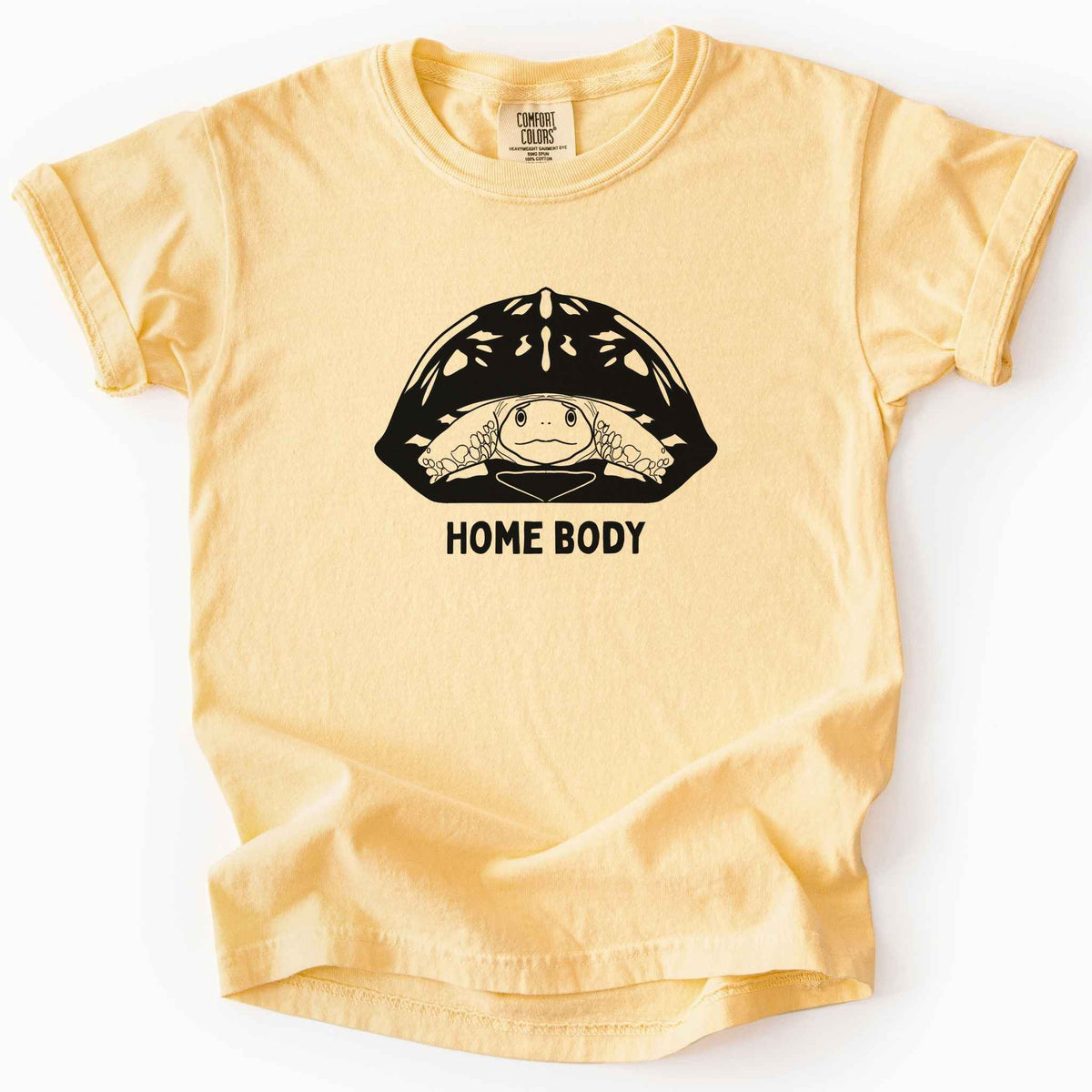 Butter "Home Body" kids t-shirt on Comfort Colors tee, featuring a bold black graphic of a turtle peeking out from its shell above simple lettering. Funny turtle lover gift shirt for introverts and reptile enthusiasts.