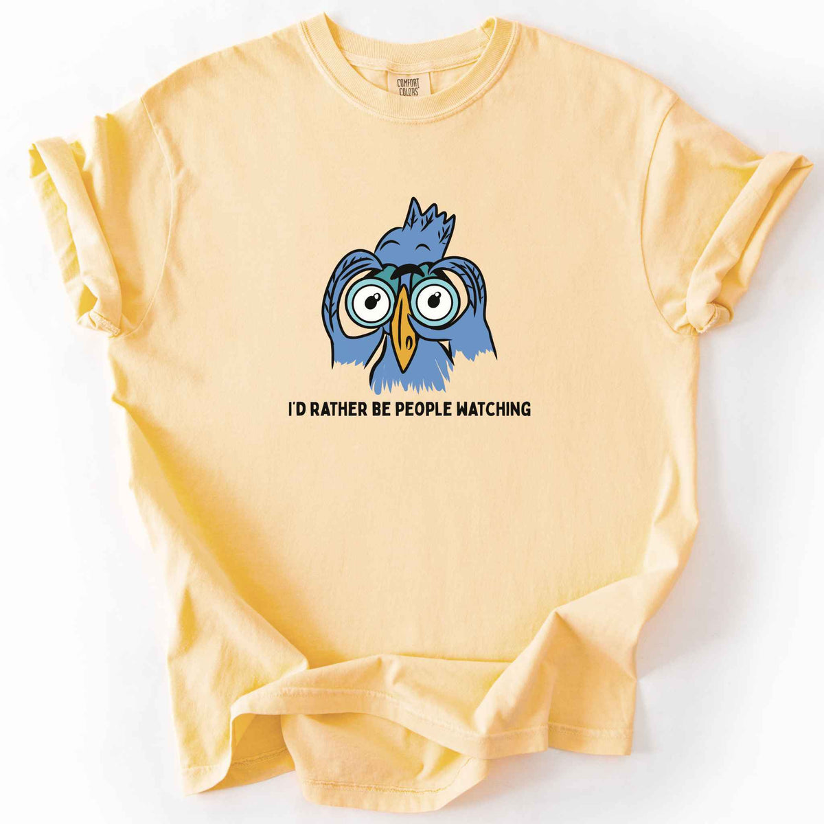 Butter "I'd Rather Be People Watching" t-shirt on Comfort Colors tee, featuring a cartoon blue bird holding binoculars up to its eyes. Funny birdwatcher gift shirt for bird lovers and introverts.