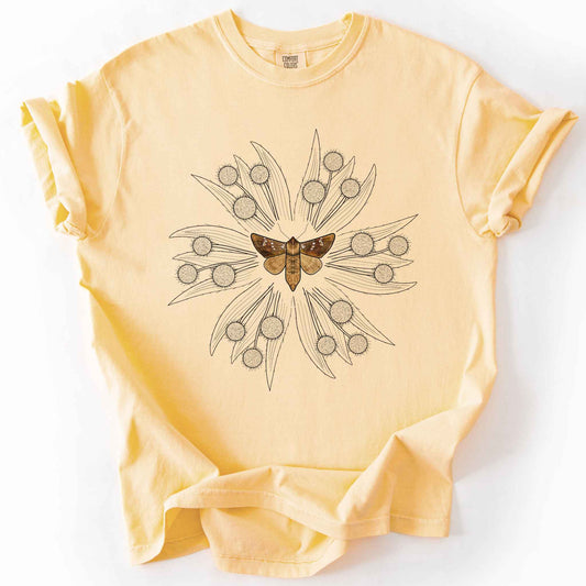 Butter endangered moth t-shirt on Comfort Colors tee, featuring a realistic Rattlesnake Master Borer Moth (Papaipema eryngii) at the center of a mandala style burst of hand drawn thistle flowers. Nature lover and moth enthusiast gift shirt for entomology and botanical illustration fans.