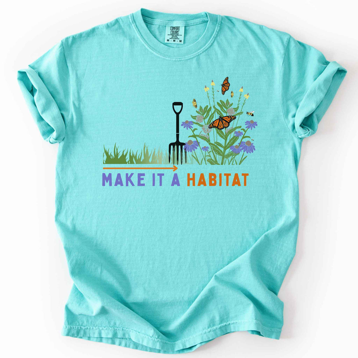 Chalky mint "Make It a Habitat" t-shirt on Comfort Colors tee, featuring a garden fork beside coneflowers and milkweed with monarch butterflies and bees, transforming grass into wildflowers. Gardener and native plant gift shirt for pollinator conservation fans.