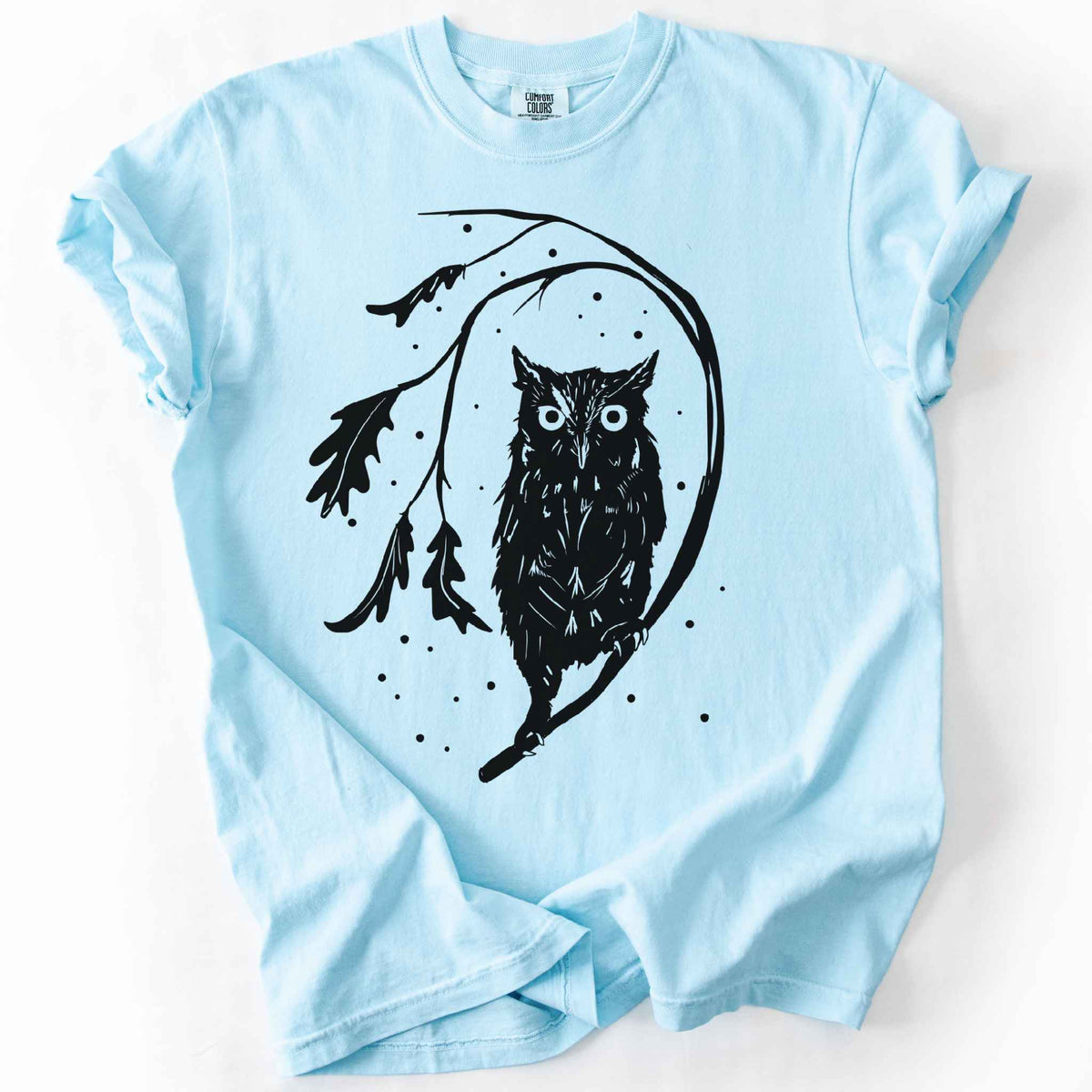 Chambray "Eastern Screech starry night" owl t-shirt on Comfort Colors tee, featuring a bold black illustration of a screech owl perched on a leafy branch with scattered dots for stars. Birdwatcher and owl lover gift shirt for wildlife and nature enthusiasts.